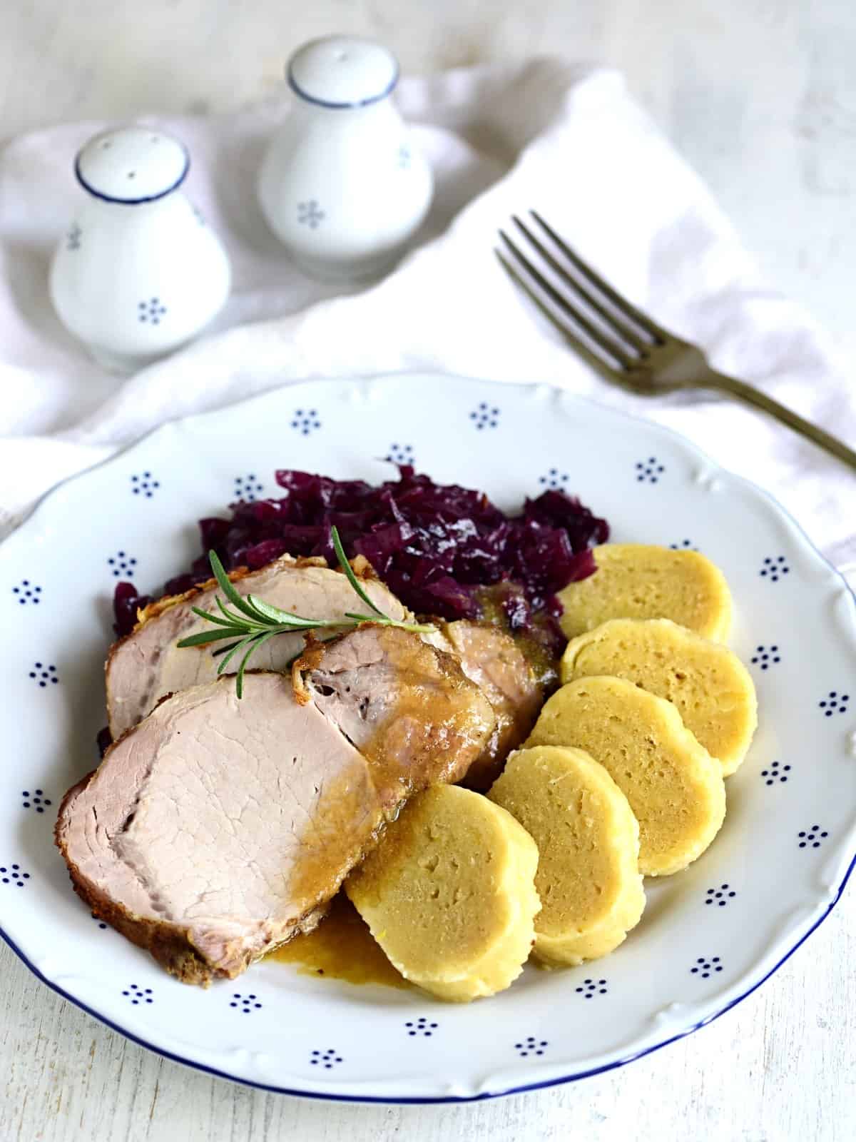 Schweinebraten mit Knödeln und Rotkohl serviert. 