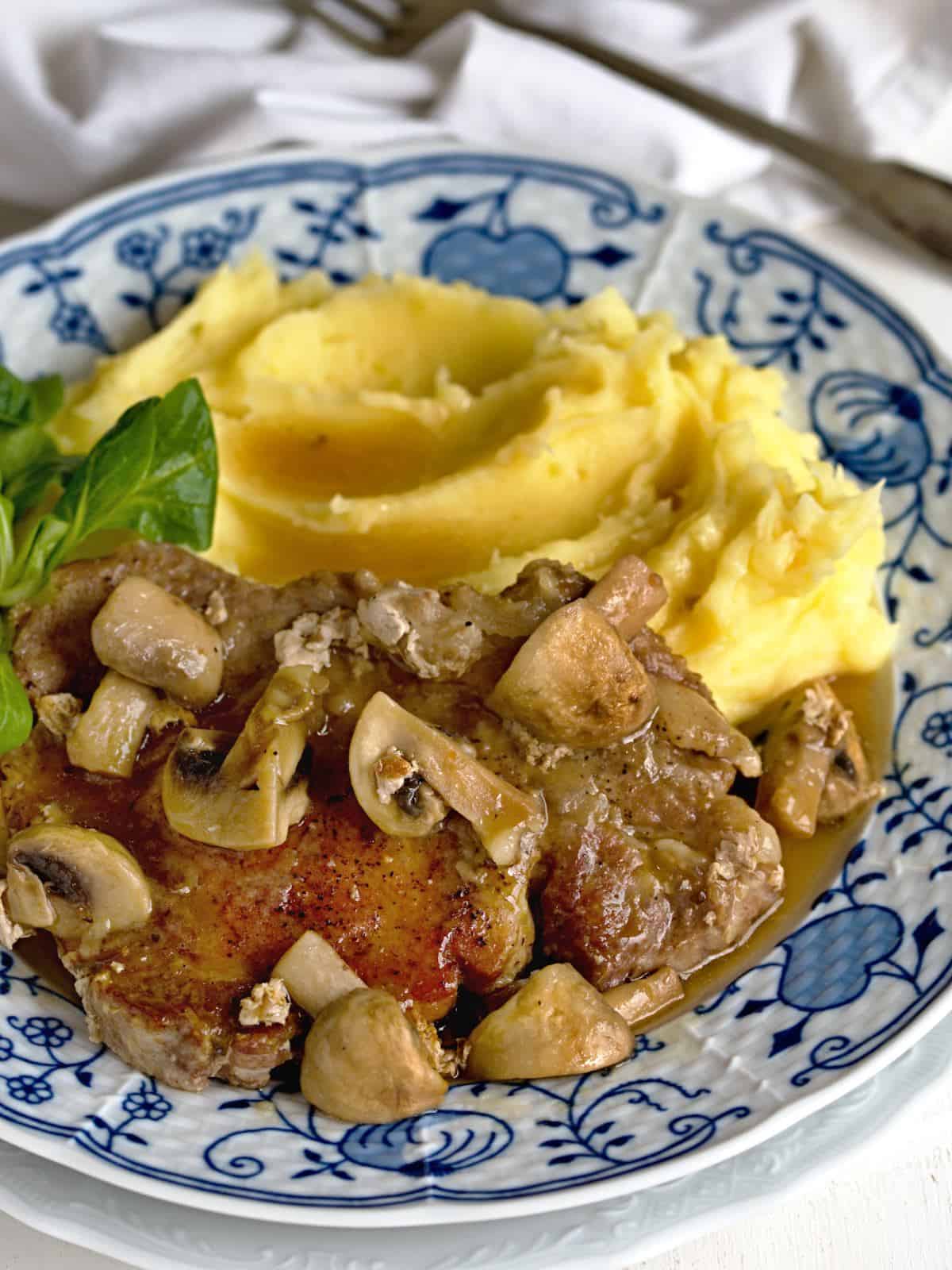 Schweinesteaks mit Champignons mit Kartoffelpüree servieren.