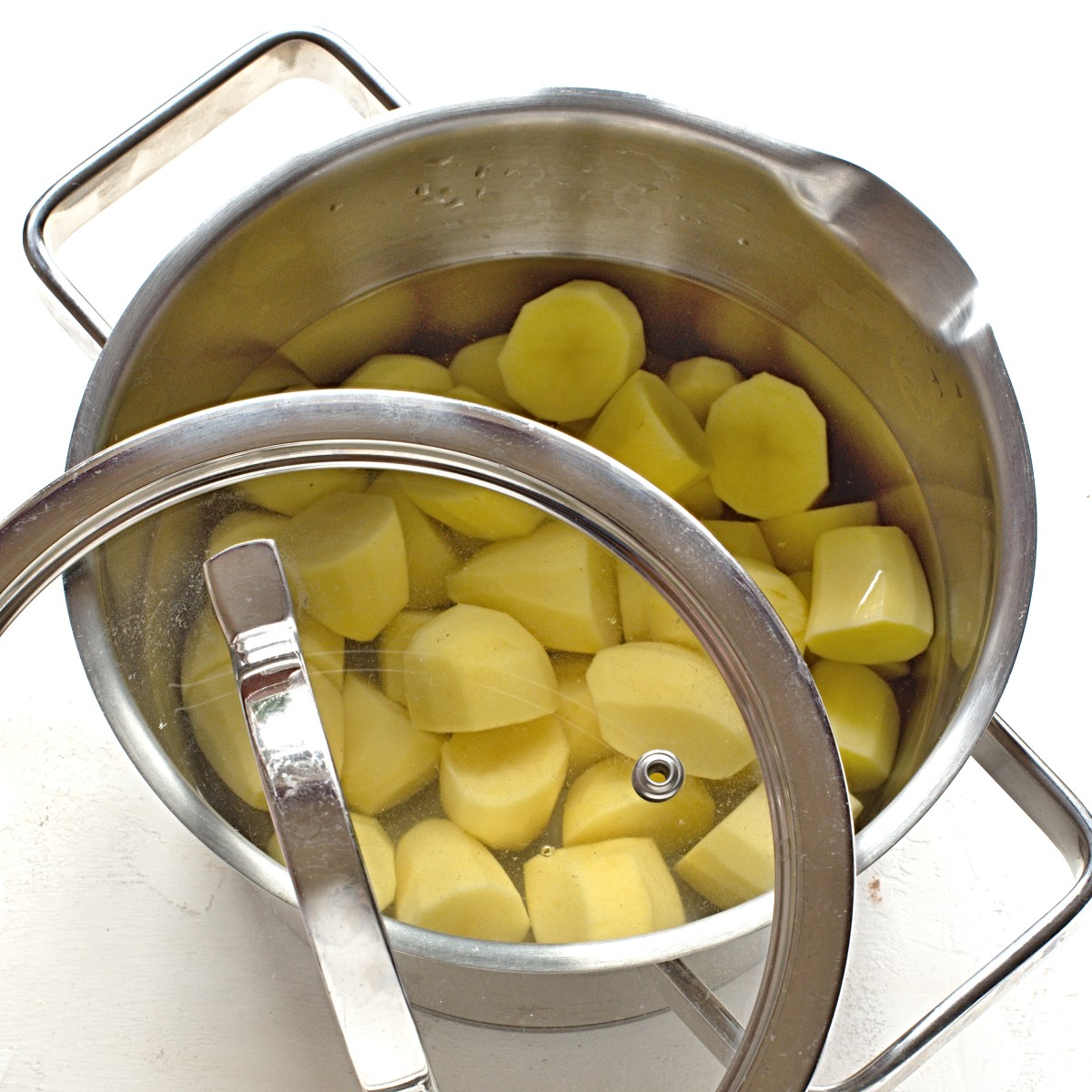 Geschälte Kartoffeln in einem Topf kochen lassen.