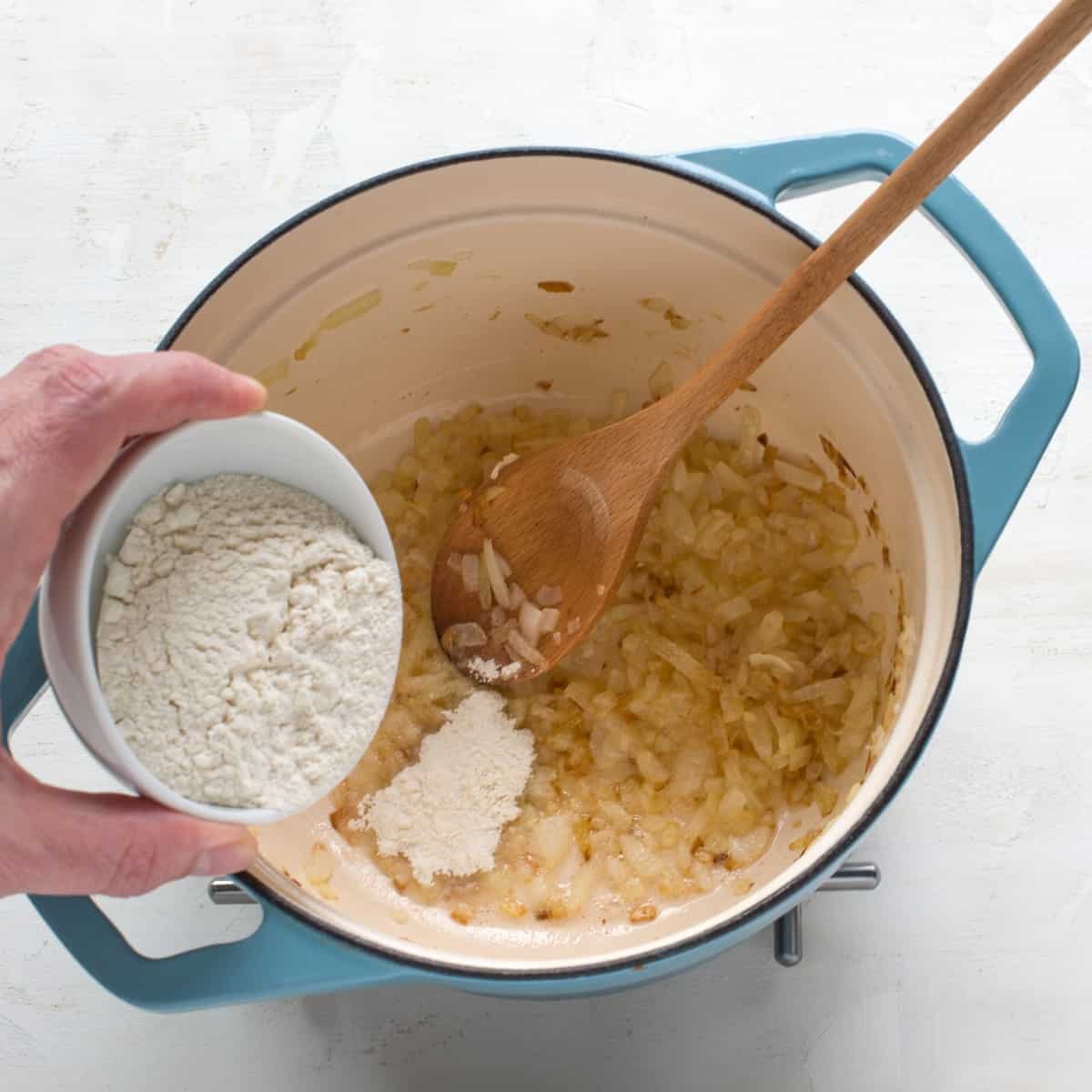 Zwiebel Mehlschwitze in einem blauen Topf zubereiten.