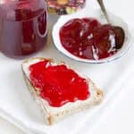 Eine Scheibe Brot bestrichen mit Johannisbeer-Marmelade.