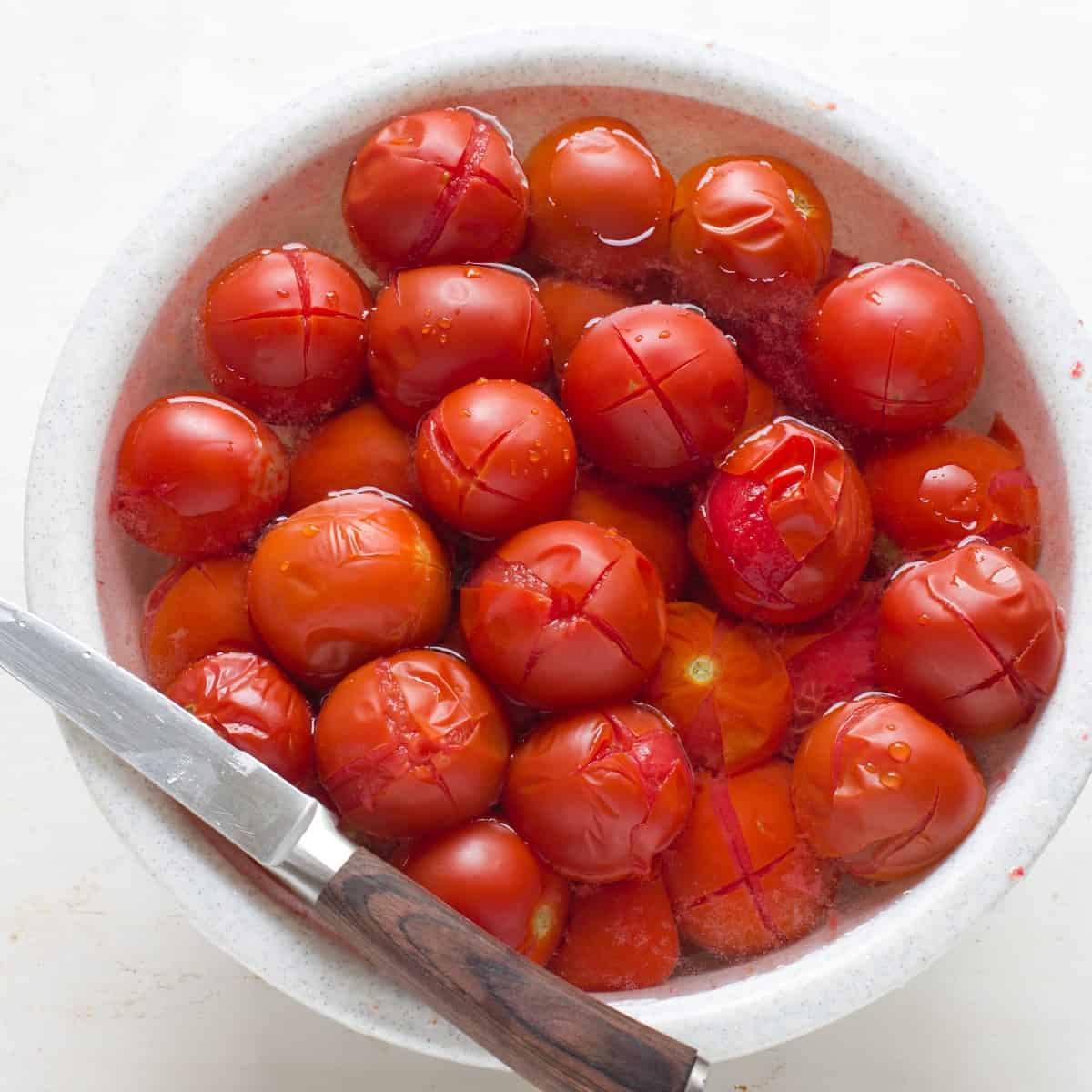 Abgeschreckte Tomaten im kalten Wasser, bereit für Schälen.