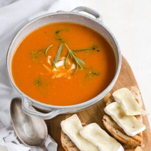 Tomatensuppe serviert mit Käse-belegten Brötchen.