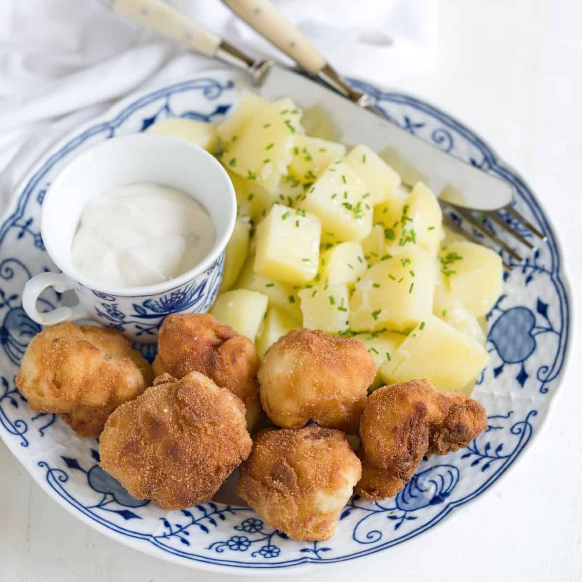 Panierter Blumenkohl serviert mit Salzkartoffeln und Sauce Tartar.