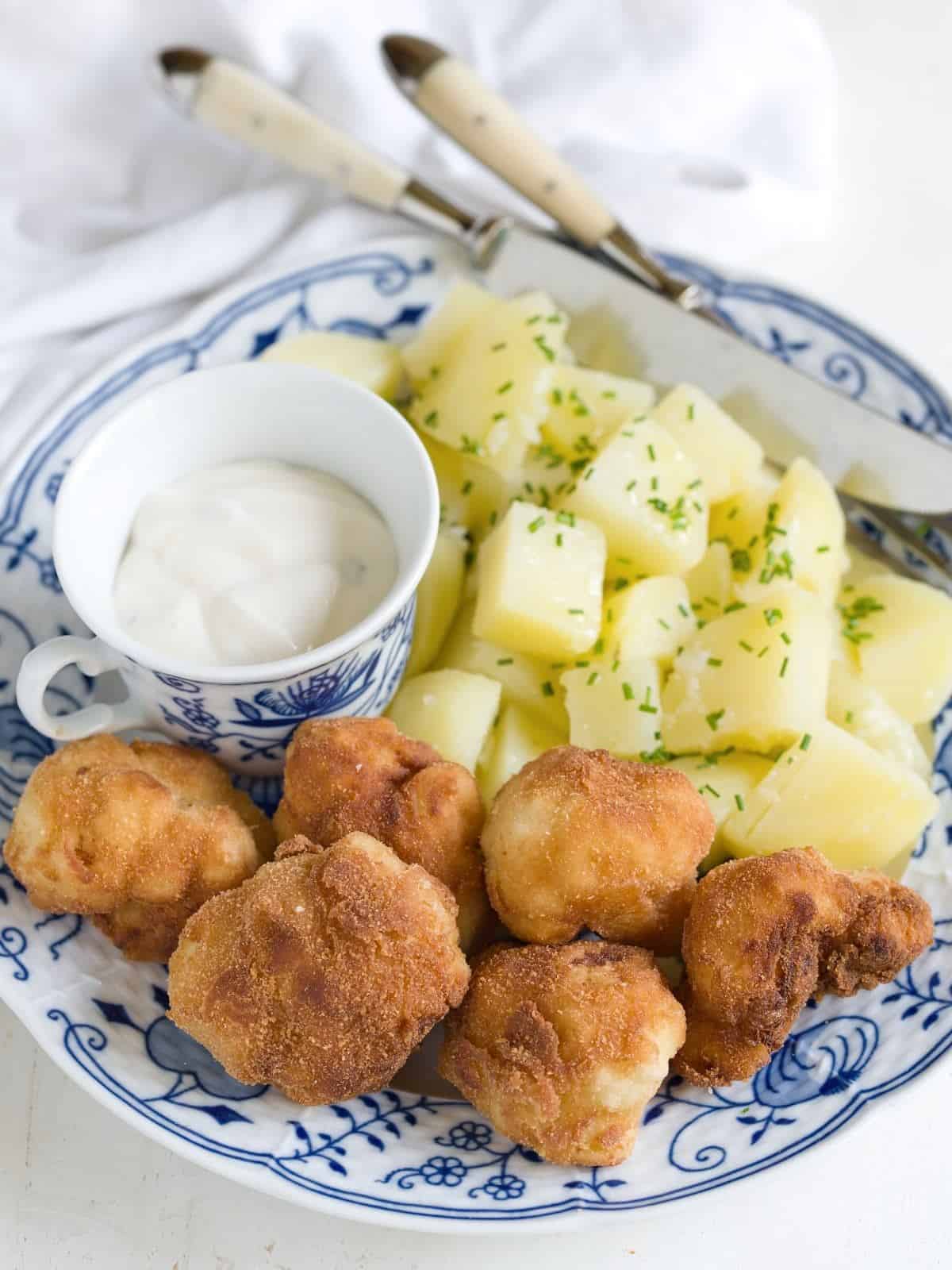 Panierter Blumenkohl serviert mit Salzkartoffeln und Sauce Tartar.